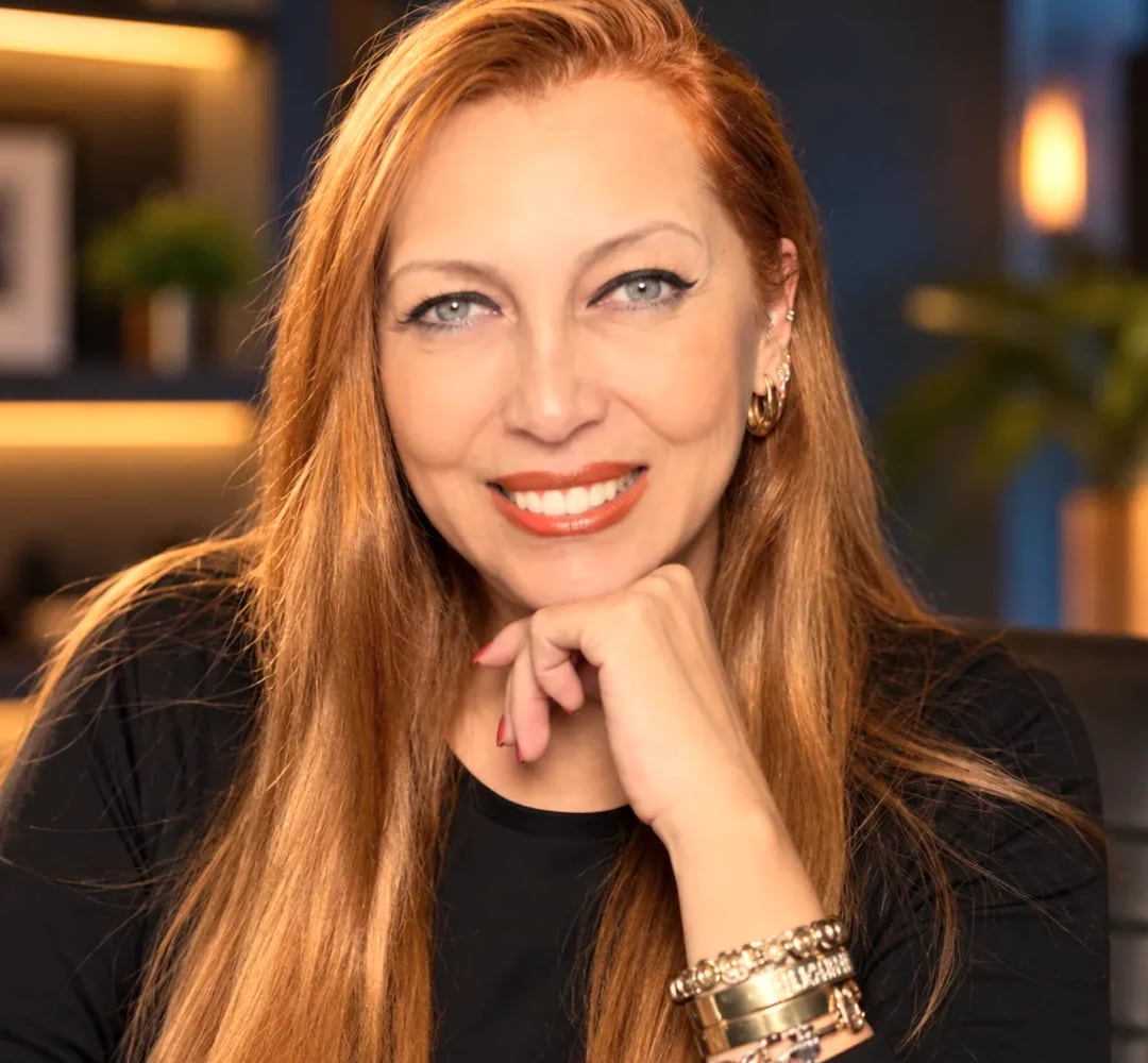 Giselle Furtado sorrindo, com a mão apoiada no queixo